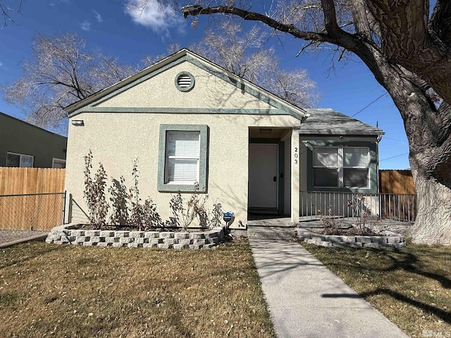 view of front of house with fence, a front lawn, and stucco siding