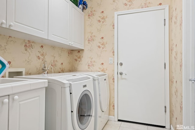 laundry room featuring light tile patterned flooring, washing machine and dryer, cabinet space, and wallpapered walls