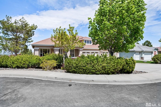 obstructed view of property with driveway, a tiled roof, and stucco siding