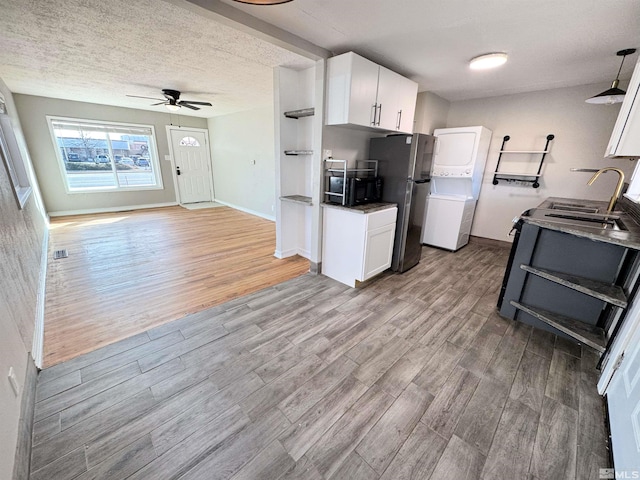 kitchen featuring dark countertops, freestanding refrigerator, white cabinetry, a textured ceiling, and light wood-type flooring