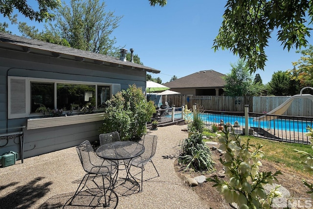 view of pool with a fenced in pool, a water slide, fence, and a patio