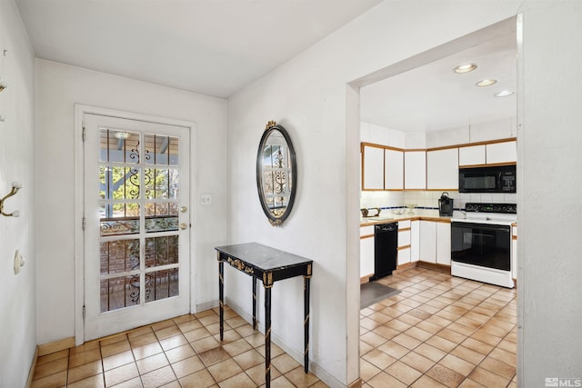 kitchen with light tile patterned floors, tasteful backsplash, light countertops, white cabinetry, and black appliances