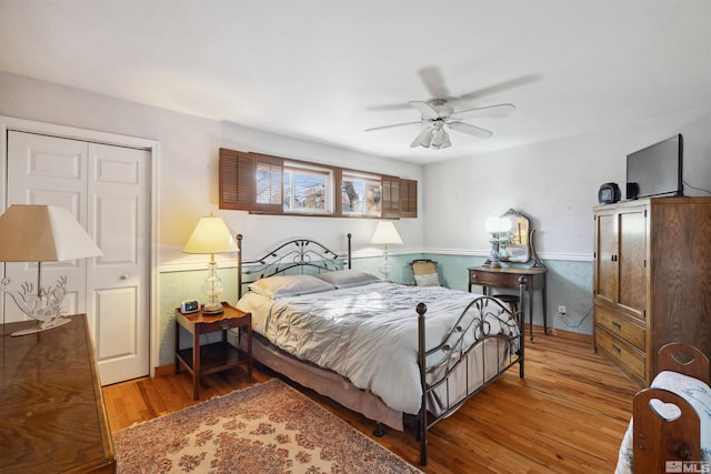 bedroom featuring light wood finished floors, a ceiling fan, a closet, and wainscoting