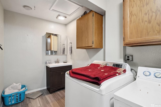 clothes washing area featuring washing machine and clothes dryer, cabinet space, light wood-style floors, attic access, and baseboards