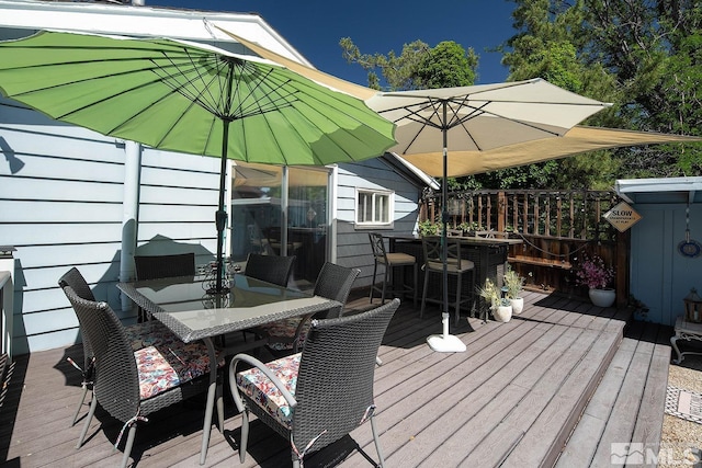 deck featuring outdoor dining space and a bar