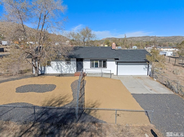 ranch-style home with a garage, fence, a mountain view, and concrete driveway