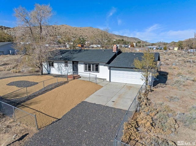 single story home featuring concrete driveway, an attached garage, fence, and a mountain view