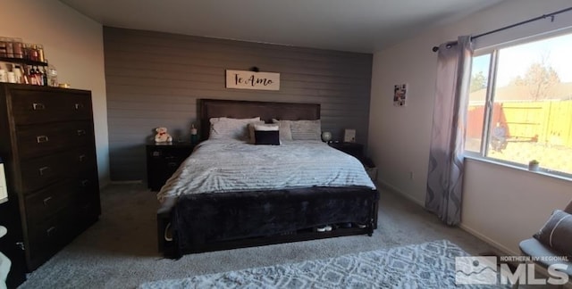 bedroom with carpet, wooden walls, and baseboards