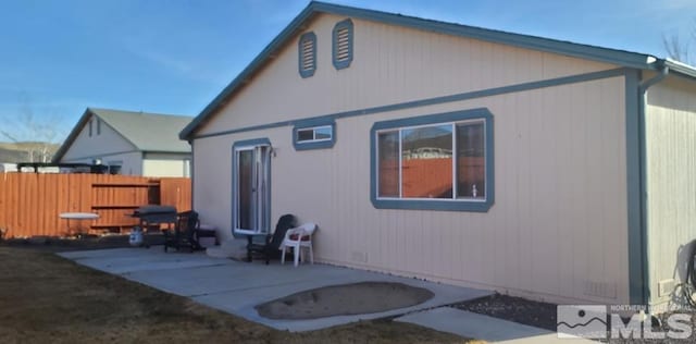 rear view of house with crawl space, a patio area, and fence