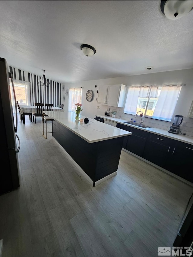 kitchen with plenty of natural light, freestanding refrigerator, dark cabinetry, and a sink