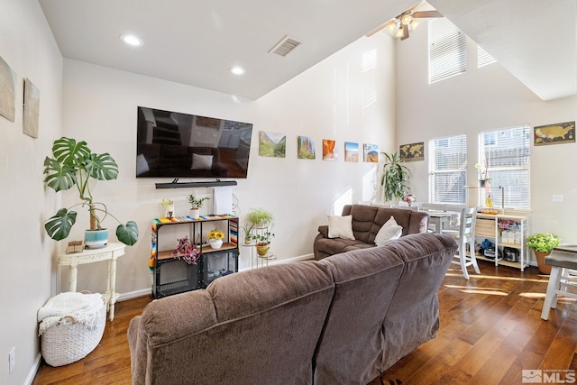 living area with a wealth of natural light, dark wood-style flooring, visible vents, and baseboards