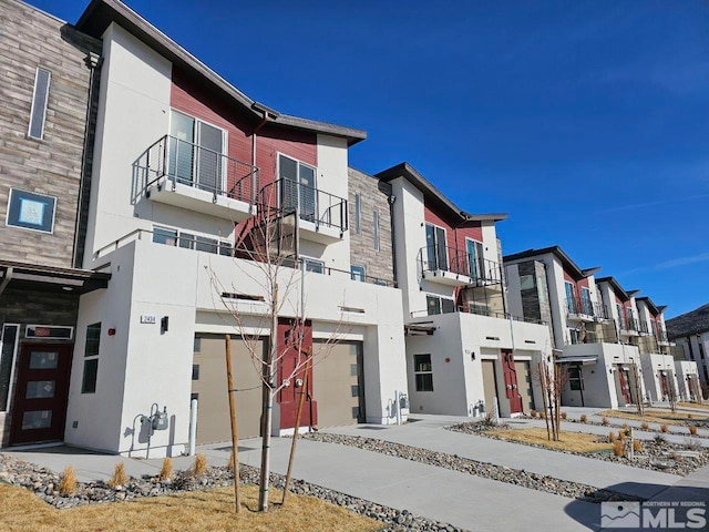 view of front of home featuring a garage, driveway, a residential view, and stucco siding