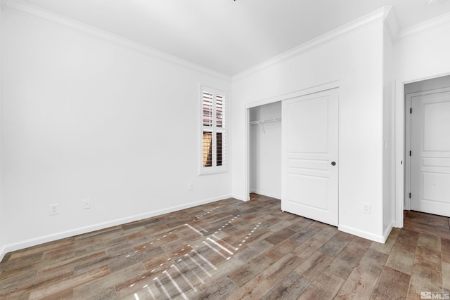 unfurnished bedroom with baseboards, a closet, wood finished floors, and crown molding