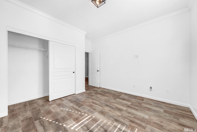 unfurnished bedroom with baseboards, a closet, wood finished floors, and crown molding