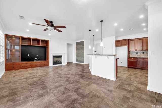 kitchen featuring an island with sink, ceiling fan, a breakfast bar area, open floor plan, and pendant lighting