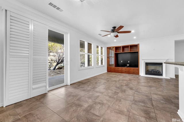 unfurnished living room featuring ceiling fan, visible vents, baseboards, a glass covered fireplace, and crown molding