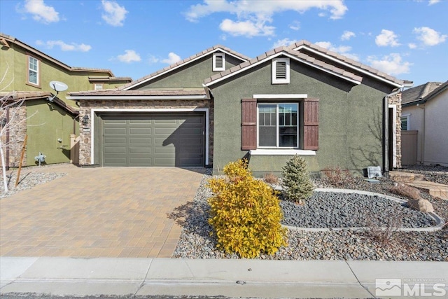 view of front of property featuring decorative driveway, a tile roof, an attached garage, and stucco siding