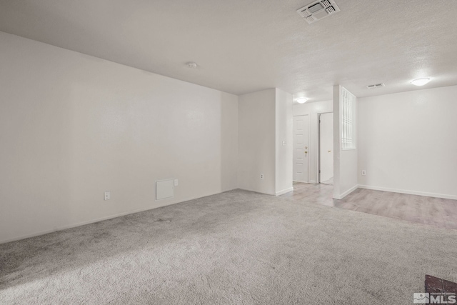 spare room with visible vents, a textured ceiling, and light colored carpet