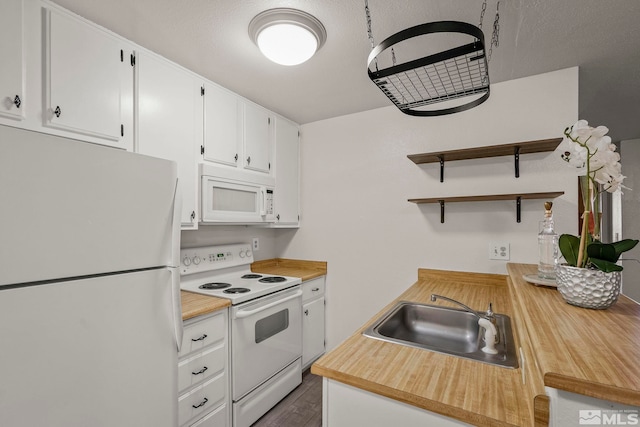 kitchen featuring white cabinets, white appliances, light countertops, and a sink