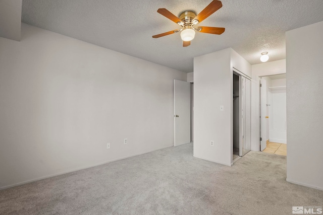 unfurnished bedroom featuring light carpet, ceiling fan, and a textured ceiling