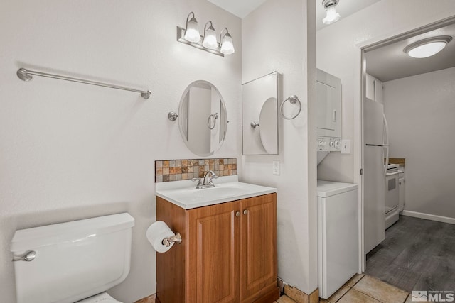 bathroom featuring tile patterned flooring, toilet, stacked washer / dryer, vanity, and backsplash