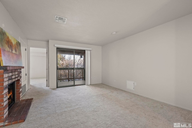 unfurnished living room featuring a brick fireplace, light colored carpet, and visible vents