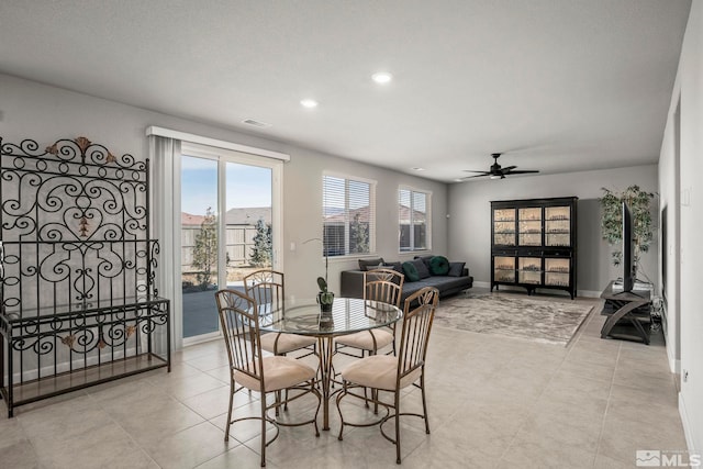 dining area featuring ceiling fan, light tile patterned flooring, a wealth of natural light, and baseboards