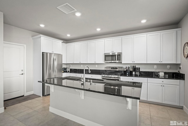 kitchen featuring a sink, visible vents, white cabinets, appliances with stainless steel finishes, and an island with sink