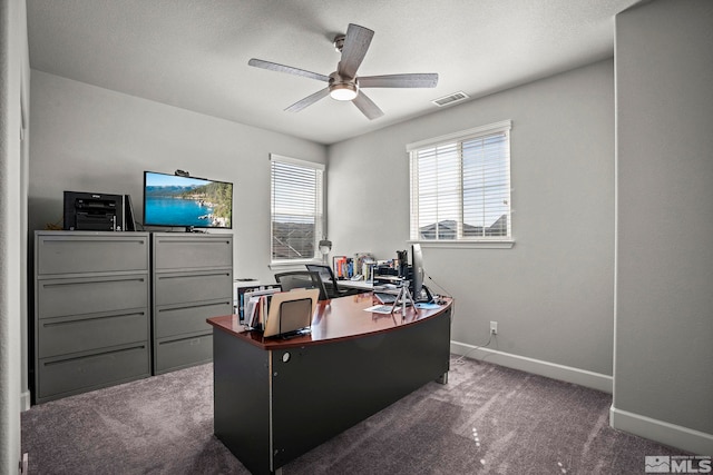 office with visible vents, baseboards, dark colored carpet, and a ceiling fan