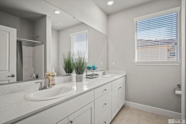 bathroom featuring double vanity, a shower with shower curtain, a sink, and baseboards