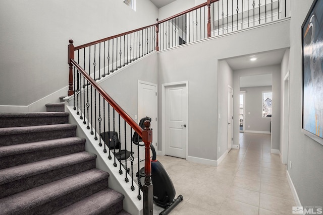 stairway with tile patterned flooring, a high ceiling, and baseboards