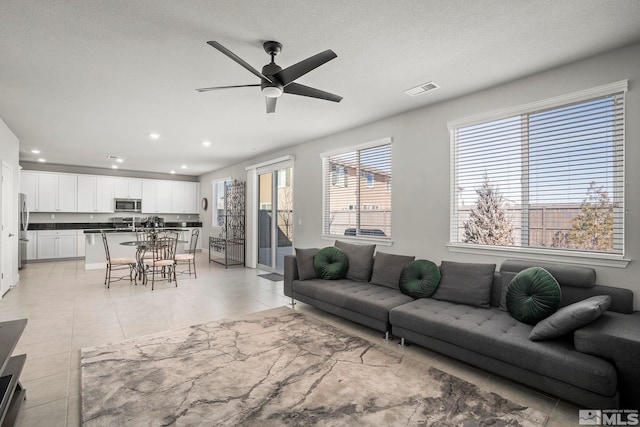 living area featuring light tile patterned floors, a textured ceiling, recessed lighting, visible vents, and a ceiling fan