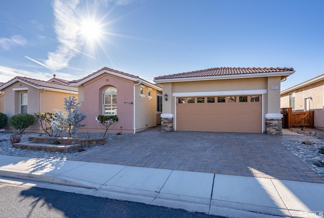 view of front of house with decorative driveway, stucco siding, an attached garage, stone siding, and a tiled roof