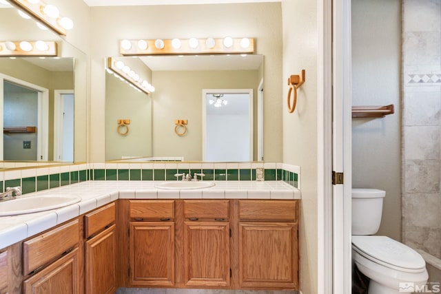 bathroom with double vanity, tasteful backsplash, a sink, and toilet