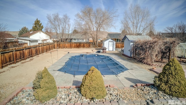 view of swimming pool with a fenced in pool, a fenced backyard, an outbuilding, a storage unit, and a patio area