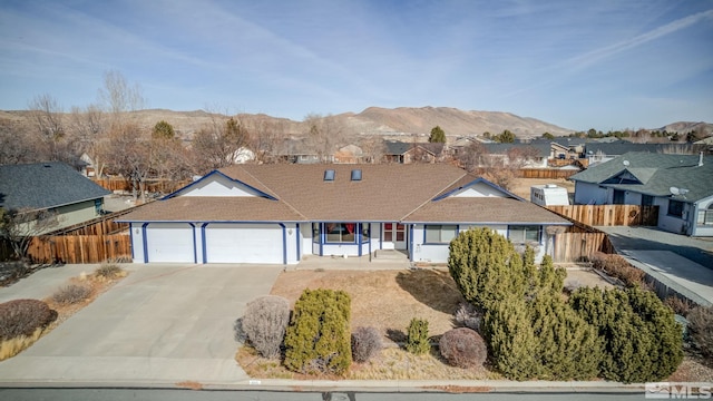 ranch-style house with a garage, driveway, a residential view, fence, and a mountain view