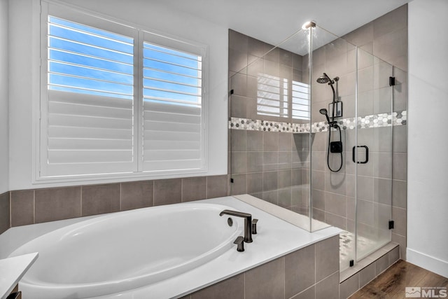 bathroom featuring a garden tub, a shower stall, and wood finished floors