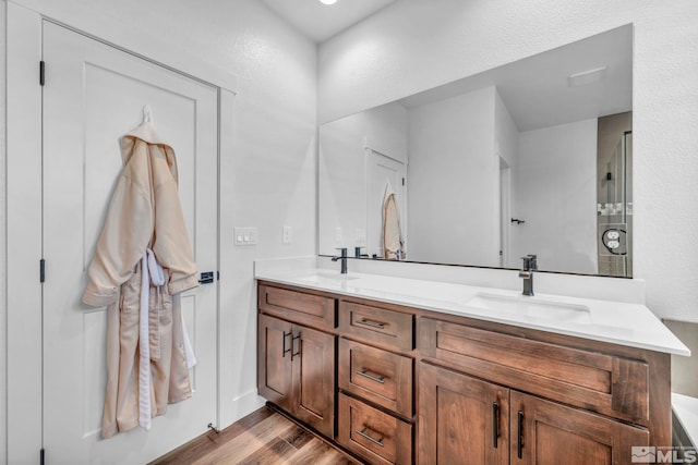 full bath with double vanity, a sink, and wood finished floors