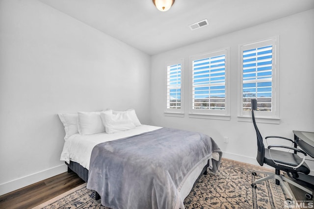 bedroom featuring wood finished floors, visible vents, and baseboards