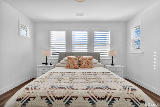 bedroom featuring dark wood-style floors, visible vents, multiple windows, and baseboards