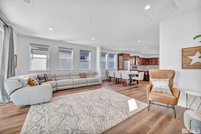 living area with light wood finished floors, visible vents, and recessed lighting