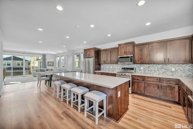 kitchen with a center island, a breakfast bar area, tasteful backsplash, light countertops, and appliances with stainless steel finishes