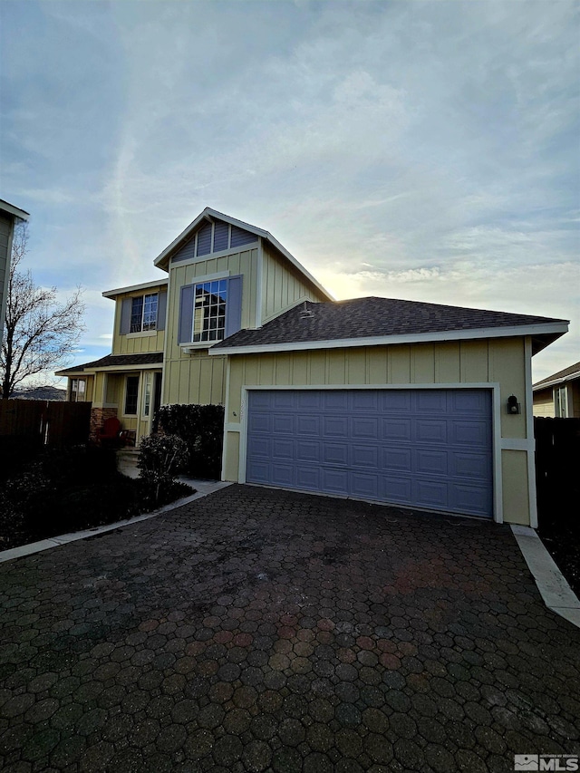 view of front of house with a shingled roof, decorative driveway, an attached garage, and board and batten siding