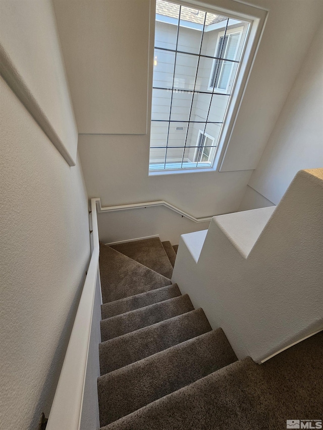 stairs featuring a healthy amount of sunlight and a textured wall