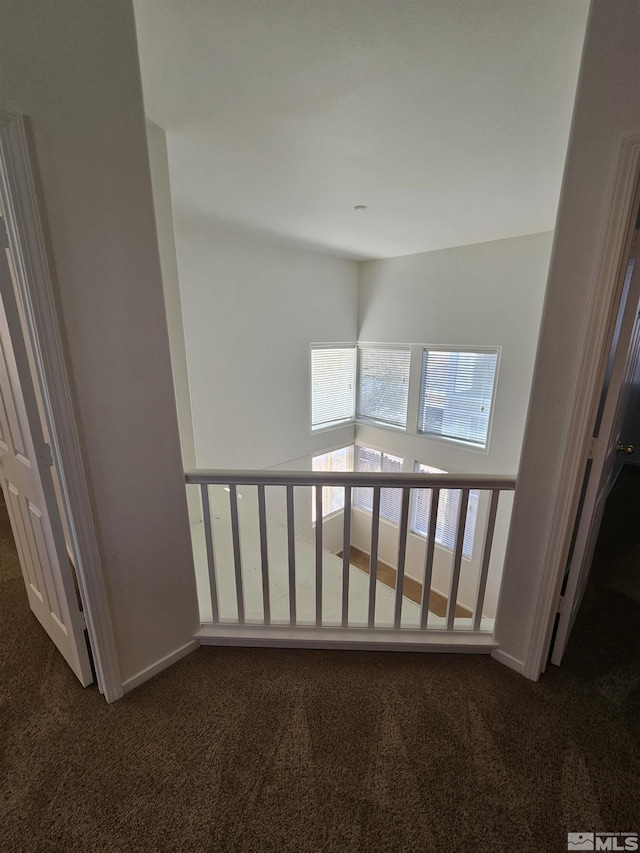 corridor with dark colored carpet and baseboards