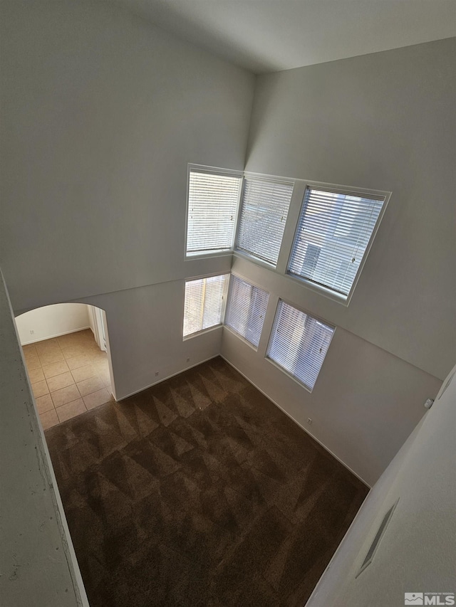 tiled spare room featuring carpet floors