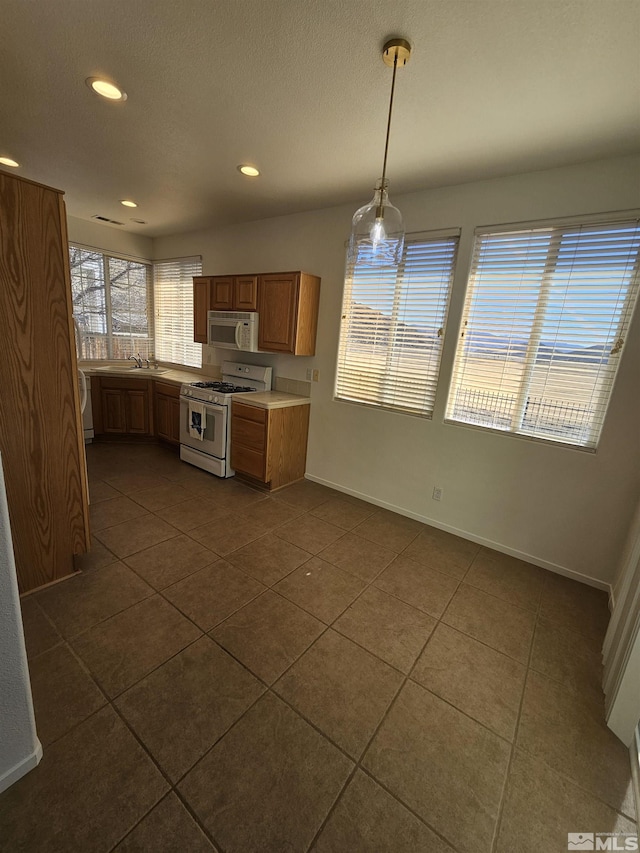 kitchen featuring light countertops, white appliances, decorative light fixtures, and dark tile patterned floors