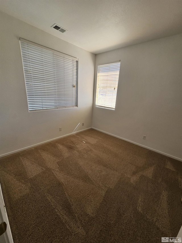 unfurnished room featuring carpet, visible vents, and baseboards