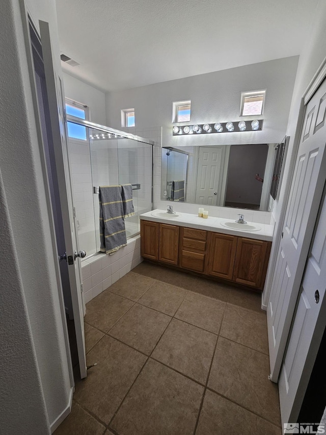 full bath with double vanity, tiled shower / bath, visible vents, and a sink