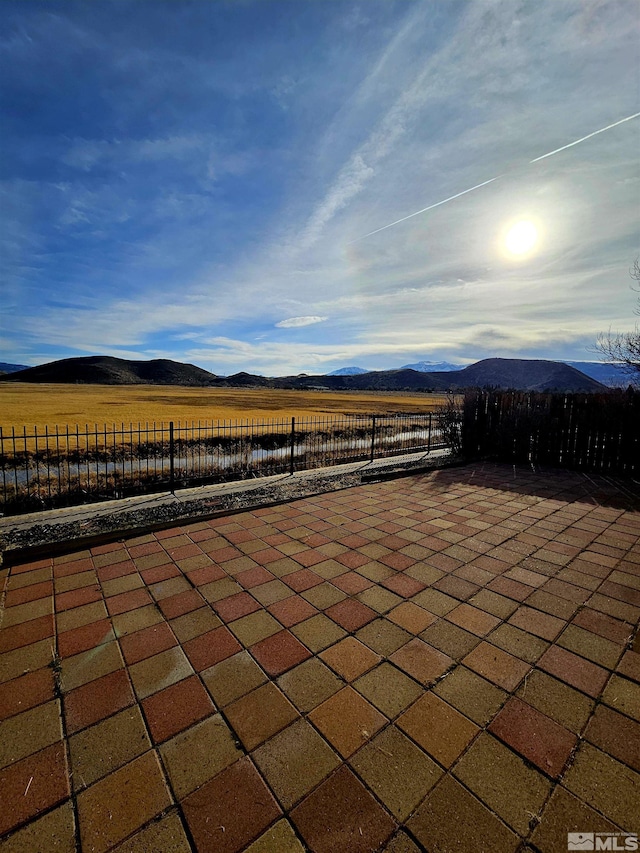 view of patio featuring a rural view, fence, and a mountain view